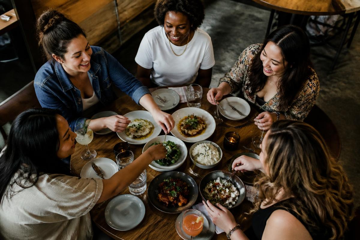 Five women sharing plates of food around a restaurant table